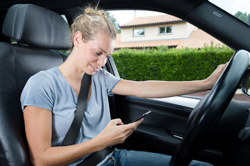 woman texting message by smart phone while on a car