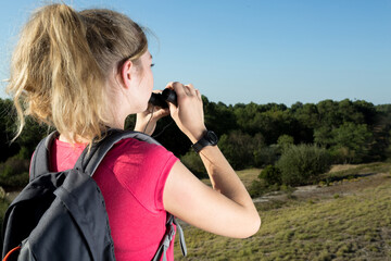 female hiker looking in binoculars enjoying view