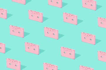Creative vintage pattern made of pink cassette tapes on light blue background. Summer tropical concept.