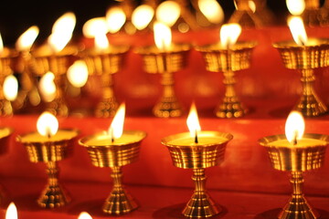 Fototapeta premium Buddhist Altar Candles at Religious 108 Butter Lamp Festival in Temple Monastery. Beautiful Tranquil Scenic View of Oil Lamps and Swaying Flame for Praying
