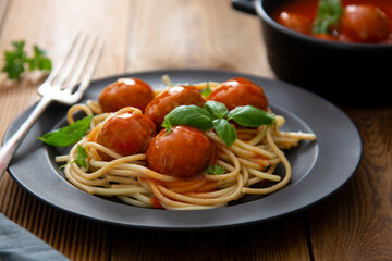 Spaghetti with eatballs tomato sauce , basil leaves in black mate plate on wooden background, delicious mediteranean food