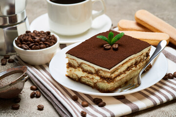 Portion of Traditional Italian Tiramisu dessert and savoiardi cookies on grey concrete background
