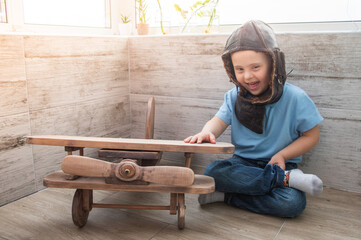 Boy with Down syndrome in a pilot's helmet next to the plane.
