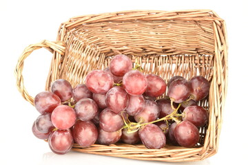 Fototapeta na wymiar A bunch of fresh organic, juicy, ripe, sweet grapes with a wicker basket of vines, close-up, on a white background.