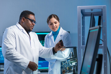 Diverse team of microelectronic engineers discuss current developments in a science lab. Workplace...