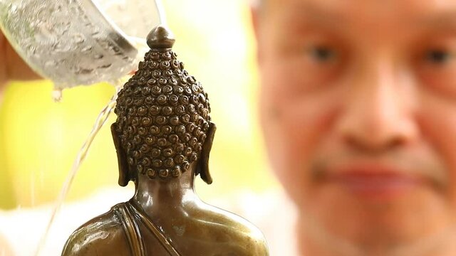 Blurred man Sprinkle water onto a Buddha Statue in Songkran  festival  Chiangmai Thailand.