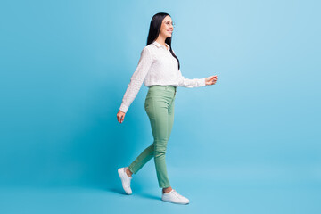 Obraz premium Full size profile side photo of young attractive woman happy positive smile go walk step meeting isolated over blue color background