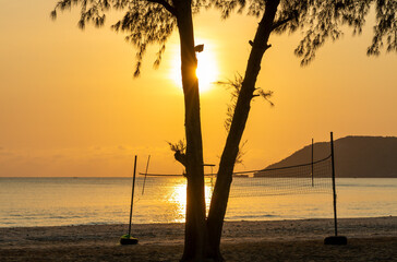 View of the sunrise through the volleyball net. Beautiful exotic beach landscape at the sunrise