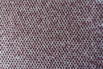 Surface of thick pink, grey and white woolen fabric with diamonds pattern from above