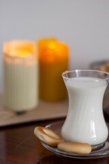 Candles, glass with milk and cookies on the table