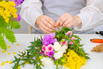 Florist at work: woman making fashion modern bouquet of different flowers on wight background.