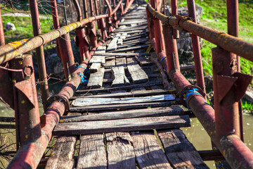 Old footbridge with balustrade and broken wooden planks 