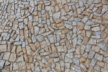 Standard view of granite sidewalk with irregular pairing, characteristic texture with moss in the joints