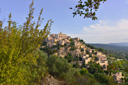 Gordes (84220) à travers les arbres domine sa vallée, dans le département du Vaucluse en région Provence-Alpes-Côte-d'Azur, France