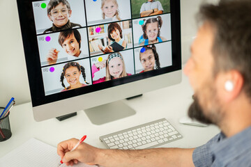 Male teacher having online conference with school children working at home