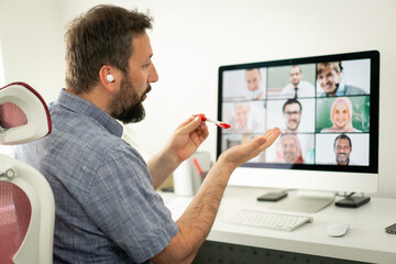 Mid adult man having online conference working at home