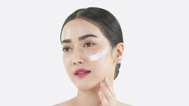 Beauty concept of 4k Resolution. Beautiful girl is happily applying cream on her face on a white background.