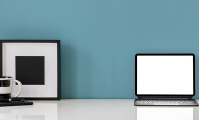 Mockup blank screen tablet and wooden picture frame and white table with blue wall background.