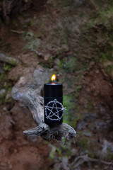 Magic pentagram amulet and black candle in forest. Black magic esoteric ritual. Mysticism,...