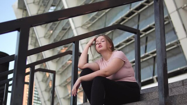 Tired overweight woman sitting on stairs after workout, lack of motivation