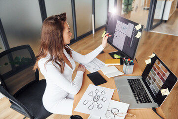 Using laptop. Young adult woman in formal clothes is indoors in the office