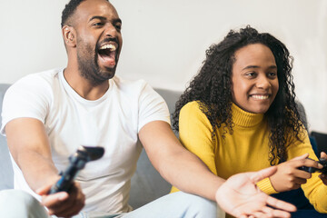 black couple playing video game with enthusiasm at home.