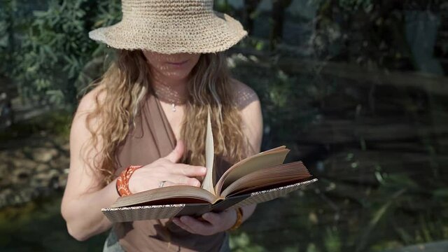 Woman reading vintage classic literature book outside in the sunlight