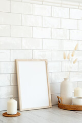Blank picture frame mockup and home decor on table. White tiles bricks on background. Minimal Scandinavian style interior