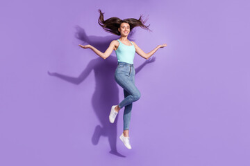 Fototapeta na wymiar Full length portrait of charming person jumping raise hands hair flying isolated on purple color background