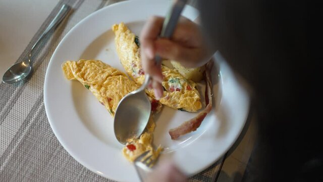Asian girl eating egg omelet with vegetable, tomato, cheese and herb in hotel restaurant in morning 