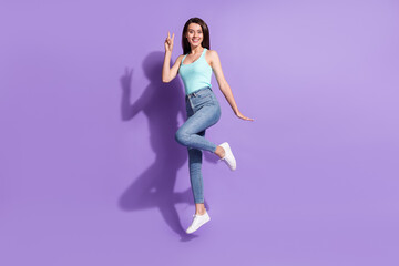 Full length photo of young happy funky woman jump up air show v-sign isolated on purple color background