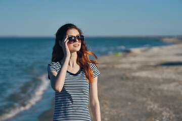 portrait of woman in t-shirt and glasses on the beach in the mountains near the sea