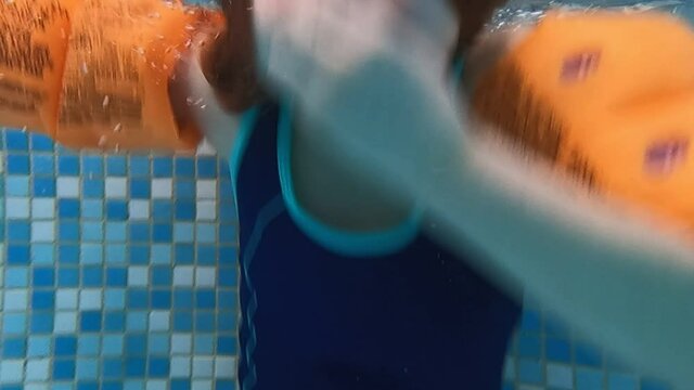 the girl in armbands dives into a swimming pool