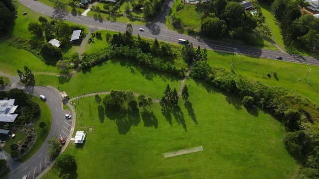 Cars Driving At Currumbin Creek Road Near Empty Park Of Chris Walton Oval At The Ecovillage Residential Community - Innovative Residential Community At Currumbin Valley, QLD, Australia. - aerial