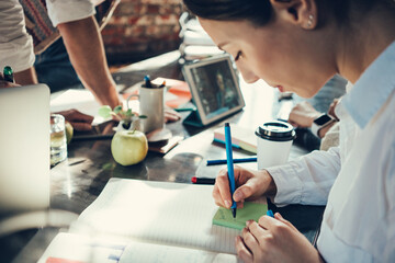 Obraz premium Woman writing mark on a sticker in loft office