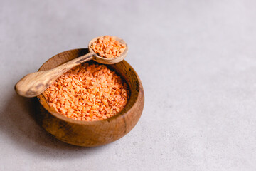 Red lentils on a wooden spoon and a bowl