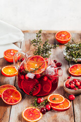 Citrus and berry tea with cranberries, blood oranges and thyme in a glass teapot.