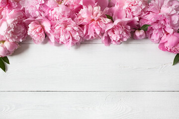 Pink peonies on a white wooden background, space for congratulations text.