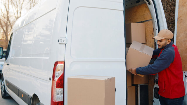 delivery men unloading cardboard boxes from truck on street. High quality photo