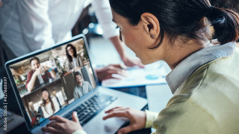 Wall mural Handsome woman using laptop for remote video call conference at the office