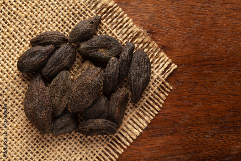 Wall mural Macro close-up of Organic Myrobalan or harad (Terminalia chebula) on the wooden top background and jute mat. Pile of Indian Aromatic Spice. Top view