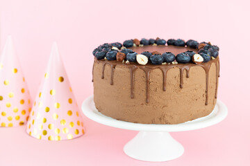 Chocolate cake with blueberries and nuts on a pink background. Free of sugar, gluten and lactose.