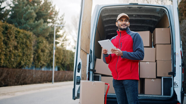 Courier with digital tablet delivering package. Mailman in front the van. High quality photo