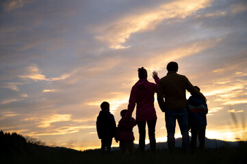 Fototapeta na wymiar Silhouette of a family standing under beautiful evening sky looking into the distance