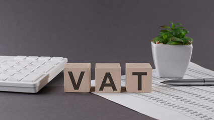 Concept word VAT on wooden blocks on gray background from green flower and chart.