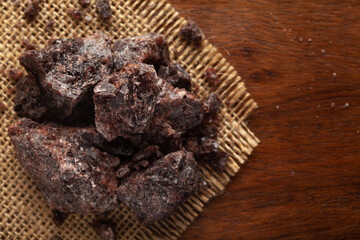 Close-up of coarse Himalayan Black  Salt (sodium chloride) edible on the wooden top background and jute mat.