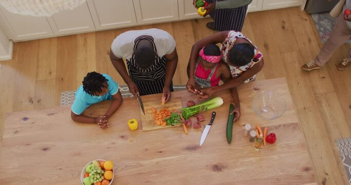 Overhead view of three generation african american family chopping vegetables in the kitchen at home