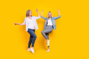 Full length body size photo of granddaughter and granny dancing chilling on weekend isolated on vivid yellow color background