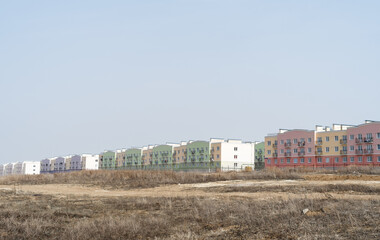 A general view of the newly built clean multi-colored apartment buildings of a new neighborhood away from the city, standing in a field. colored three-story houses for young families