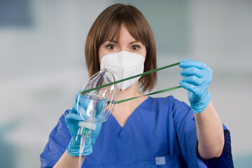 nurse is applying disposable oxygen mask for breathing support from patient view